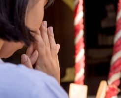 神社でお祈りをする女性
